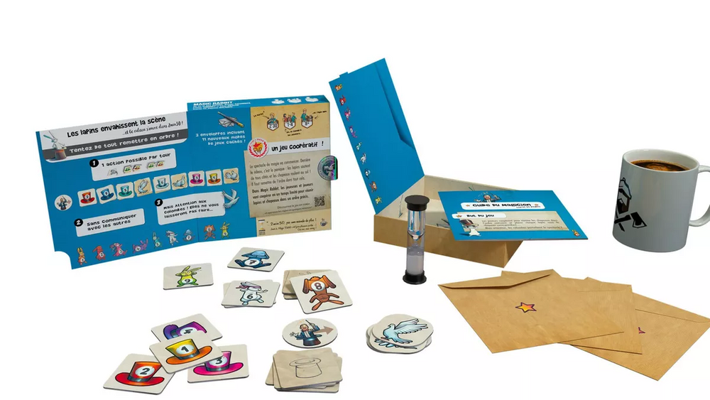 Board game components including cards, a box, and a mug on a white background