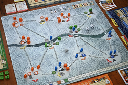 Board game with a map and various game pieces on a wooden table