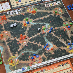 Board game with a detailed map and various game pieces on a wooden table.